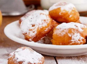 Beignets minute dorés et saupoudrés de sucre glace, servis pour le goûter.